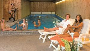 a group of people sitting in chairs near a swimming pool at Burghotel in Geislingen an der Steige