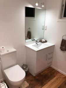 a white bathroom with a toilet and a mirror at Aorangi Highland Country Retreat in Rotorua