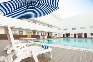 a hotel pool with a blue and white umbrella and chairs at Garden Sentral Hotel in Kuala Belait