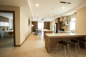 a kitchen and living room with a counter and chairs at Garden Sentral Hotel in Kuala Belait