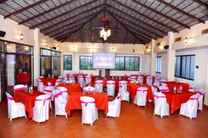 un salón de banquetes con mesas y sillas rojas y blancas en Forest Escapes Koyna, en Koynanagar