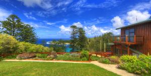 a house with a yard with a view of the ocean at Endeavour Lodge in Burnt Pine