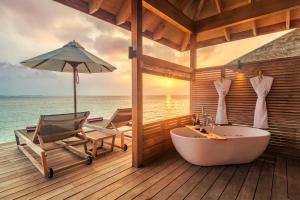 a bathroom with a tub and a chair and an umbrella at Hurawalhi Island Resort in Kuredu