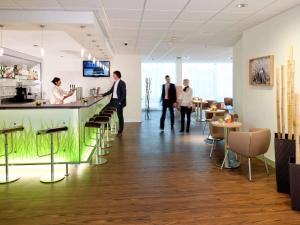 a group of people standing around a bar in a restaurant at ibis Augsburg Hauptbahnhof in Augsburg