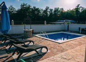 - une piscine avec 2 chaises et un parasol dans l'établissement HA-LU 1 - Holiday Relax Home, à Ružići