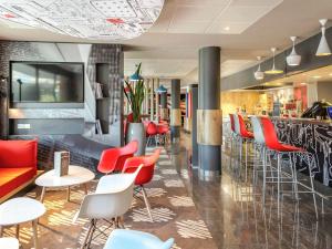 a restaurant with red and white chairs and a bar at ibis Cannes Mandelieu in Mandelieu-la-Napoule