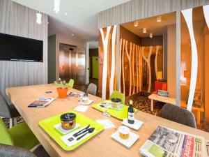 une salle à manger avec une table en bois et une télévision dans l'établissement Ibis Styles Annemasse Genève, à Ambilly