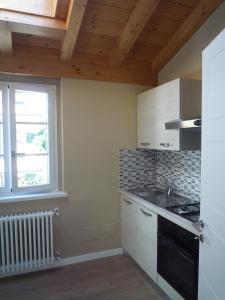 a kitchen with white cabinets and a window and a stove at Casa Il Cedro in Verbania