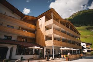 un bâtiment avec un balcon avec des parasols en face de celui-ci dans l'établissement Aktiv & Familienhotel Adlernest, à Senales