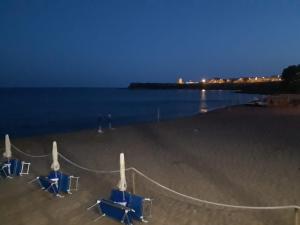a beach with blue chairs and the ocean at night at Villa Ida in Capo Rizzuto