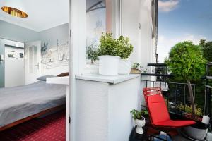 Pokój z balkonem z łóżkiem i czerwonym krzesłem w obiekcie Apartamenty Ogrodowa - Lublin 700 w mieście Lublin