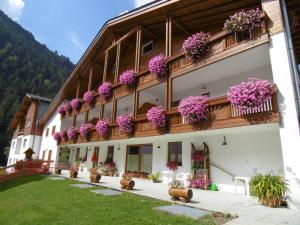 un bâtiment avec des fleurs violettes sur les balcons dans l'établissement Baita dei Pini, à Campodolcino