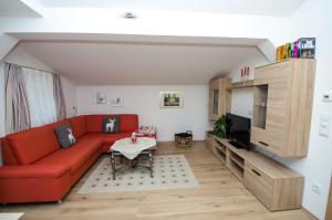 sala de estar con sofá rojo y TV en Haus Lercher, en Bramberg am Wildkogel
