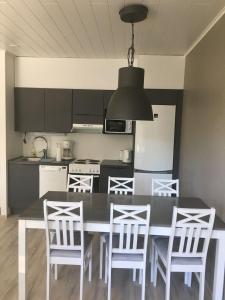 uma cozinha com uma mesa preta e cadeiras brancas em Paljakka Villas em Kotila