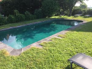 a swimming pool in the grass with a bench at Manoir d'Aubeterre in Marsat