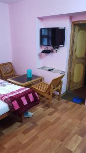 Cette chambre comprend un lit, une table et une télévision. dans l'établissement Cottage Mini For Backpackers & Small Family, à Manali