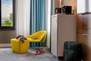 a room with a yellow chair and a suitcase at Mercure Berlin Wittenbergplatz in Berlin