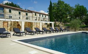 ein Swimmingpool mit Liegestühlen neben einem Gebäude in der Unterkunft Stancija Ruseti in Oprtalj