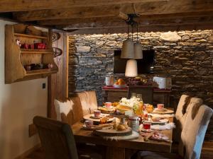 a wooden table with chairs around it with food on it at Bed & Breakfast Anisor - Parblanc in La Salle