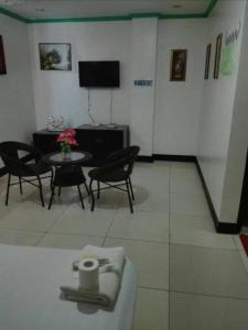 un soggiorno con tavolo, sedie e TV di Asia Novo Boutique Hotel - Kalibo a Kalibo