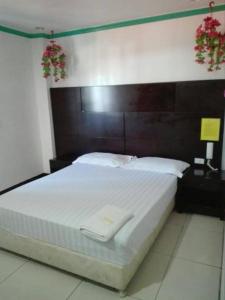 a bedroom with a large bed with a wooden headboard at Asia Novo Boutique Hotel - Kalibo in Kalibo