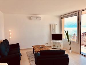 a living room with a couch and a tv and a table at Attico Palazzo di Vetro in Luino