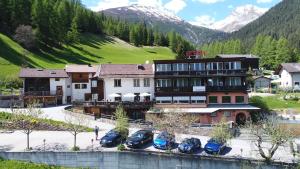 a hotel with cars parked in a parking lot next to a mountain at Hotel Sonnenhalde in Wiesen