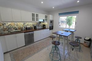 a kitchen with white cabinets and bar stools at ViVaTenerife - Gorgeous villa with heated pool in Buzanada