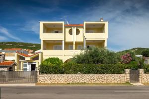 a white building with a stone wall in front of it at Apartmani Vrtlici Zdenka in Stara Novalja