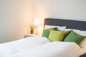 a bed with green and white pillows and a lamp at ApartWehr Business&Ferien Apartment Grün in Wehr