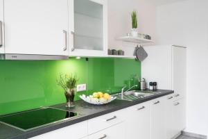 a green kitchen with a sink and a bowl of fruit at ApartWehr Business&Ferien Apartment Grün in Wehr