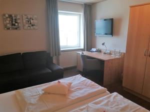 ein Hotelzimmer mit einem Bett, einem Schreibtisch und einem TV in der Unterkunft Hotel Landgasthof Euringer in Oberstimm
