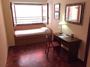 Kleines Zimmer mit einem Schreibtisch, einem Fenster und einem Bett. in der Unterkunft Centro, Colón in Alicante