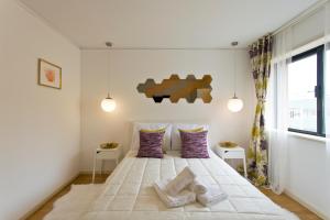 ein Schlafzimmer mit einem großen weißen Bett mit lila Kissen in der Unterkunft Amazing Comfy Flat with Balcony by Host Wise in Matosinhos