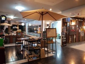 un restaurante con una mesa y una sombrilla en una tienda en The Park Land Bangna by Nudda, en Bangkok