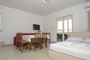 a room with two beds and a table and chairs at Apartmani Vrtlici Zdenka in Stara Novalja