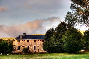 ein altes Steinhaus auf einem Feld mit Bäumen in der Unterkunft Hospedería El Pico del Fraile in Cobreros