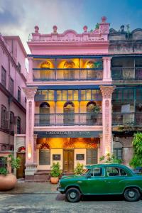 un viejo coche verde estacionado frente a un edificio en Calcutta Bungalow, en Calcuta