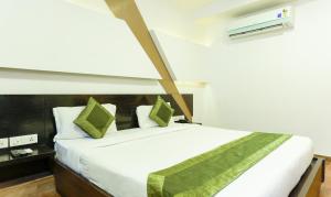 a bedroom with a large white bed with green pillows at Treebo Trend Edge St Marks Road in Bangalore