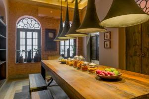 a long wooden table with a bowl of fruit and jars of honey at Calcutta Bungalow in Kolkata