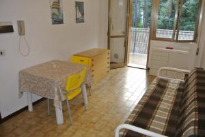 a small room with a table and a yellow chair at Appartamento SCHUBERT B in Lignano Sabbiadoro