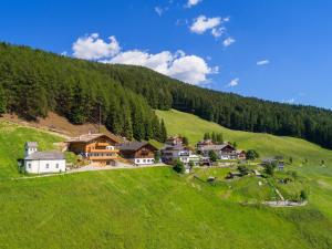ein kleines Dorf auf einem grünen Hügel mit Bäumen in der Unterkunft Taser Alm in Schenna
