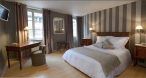 um quarto de hotel com uma cama, uma secretária e uma janela em The Originals Boutique, Hôtel de la Balance, Montbéliard em Montbéliard