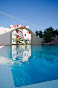 a swimming pool with blue water in front of a building at Hotel Rainbow Resort in Marsala