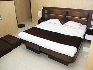 a bedroom with a large bed with a wooden headboard at Hotel Ripon Palace in Mumbai