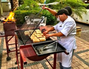 a man is cooking food on a grill at Turnberry Boutique Hotel in Oudtshoorn
