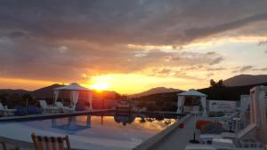 a sunset over a swimming pool with the sun setting at Luštica Apartments in Luštica