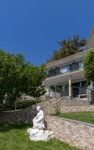 a statue sitting in the grass in front of a building at Hotel Villa Nisteri in Limenas