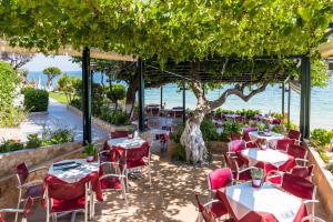 a restaurant with tables and chairs with the ocean in the background at Hotel Villa Nisteri in Limenas
