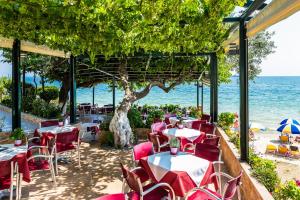 a restaurant with tables and chairs and the ocean at Hotel Villa Nisteri in Limenas